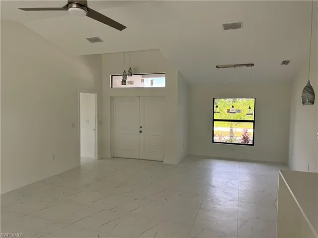 Tiled spare room featuring plenty of natural light, high vaulted ceiling, and ceiling fan