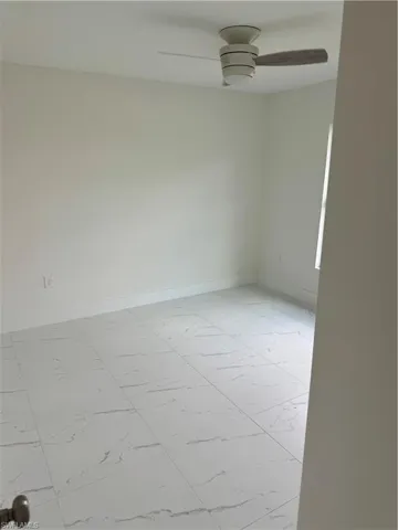 Tiled empty room featuring ceiling fan