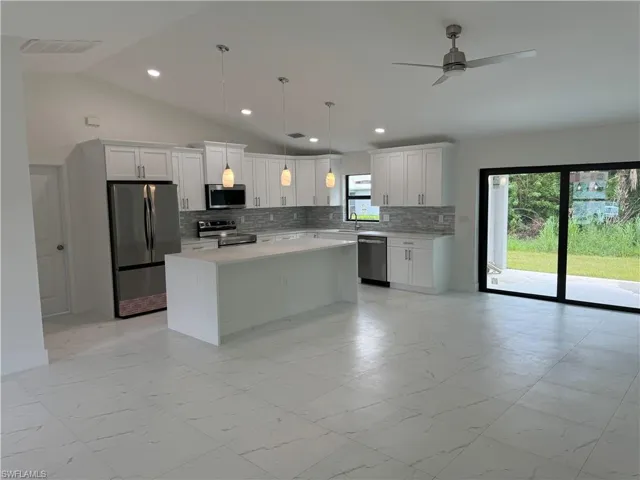 Kitchen featuring decorative light fixtures, a center island, tasteful backsplash, and stainless steel appliances
