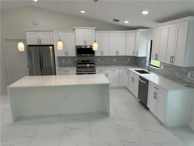 Kitchen featuring a kitchen island, stainless steel appliances, and backsplash