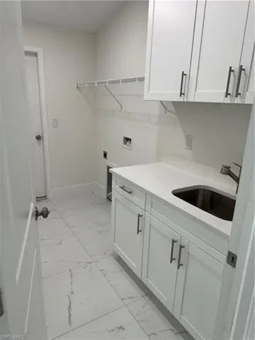 Laundry room featuring sink, electric dryer hookup, cabinets, hookup for a washing machine, and light tile patterned floors