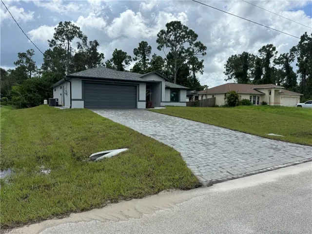Ranch-style home with a garage, cooling unit, and a front yard