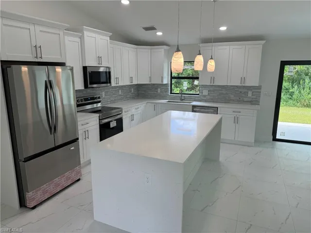Kitchen with appliances with stainless steel finishes, light tile patterned floors, tasteful backsplash, and sink