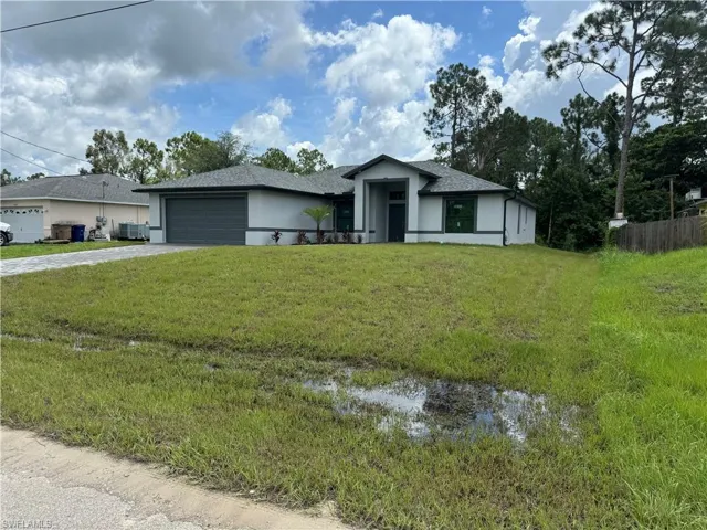 View of front of property featuring a garage and a front lawn