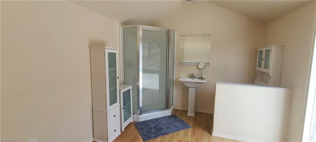 Bathroom with lofted ceiling, a stall shower, and wood finished floors