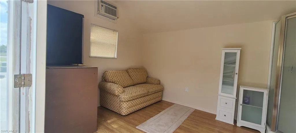Sitting room with visible vents, vaulted ceiling, and wood finished floors