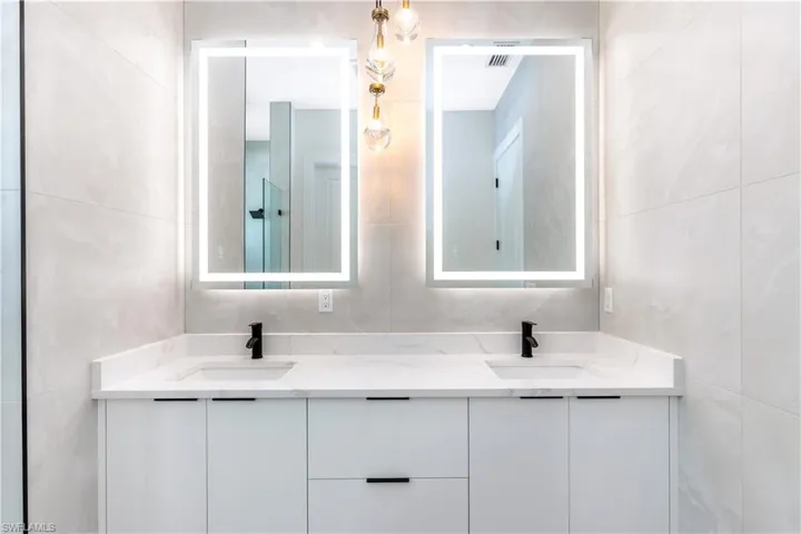 Primary Bathroom featuring tile walls and double vanity