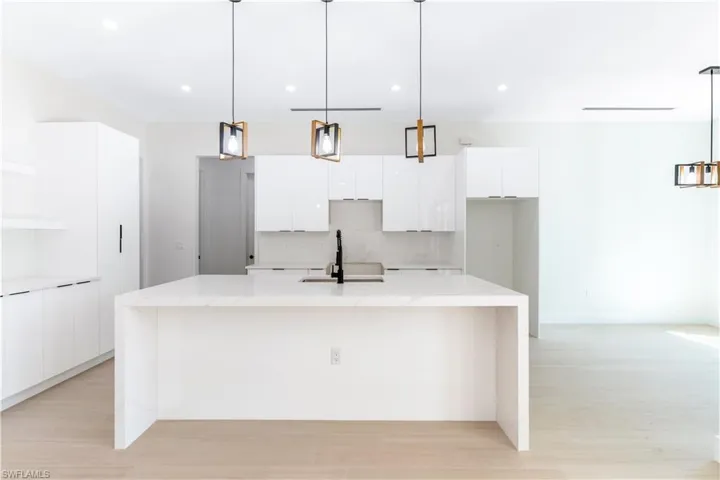 Kitchen with pendant lighting, white cabinetry, and open shelves