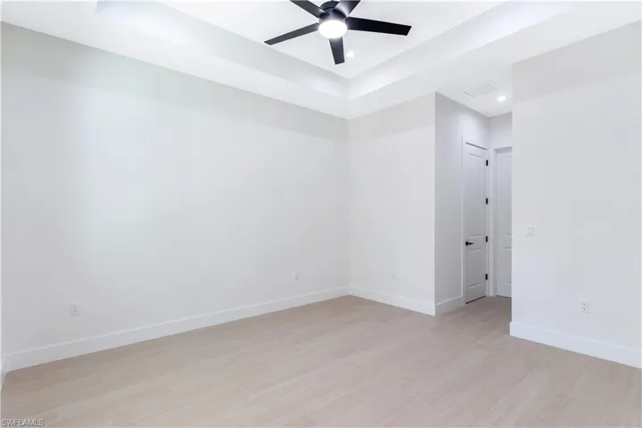 Primary bedroom featuring a raised ceiling, ceiling fan, and recessed lighting
