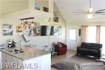 Kitchen featuring light countertops, an island with sink, ceiling fan, open floor plan, and high vaulted ceiling