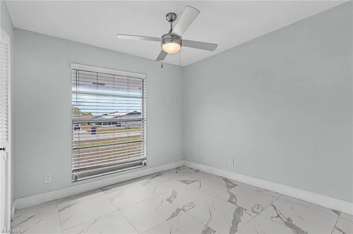 Spare room with marble finish floor, baseboards, and ceiling fan