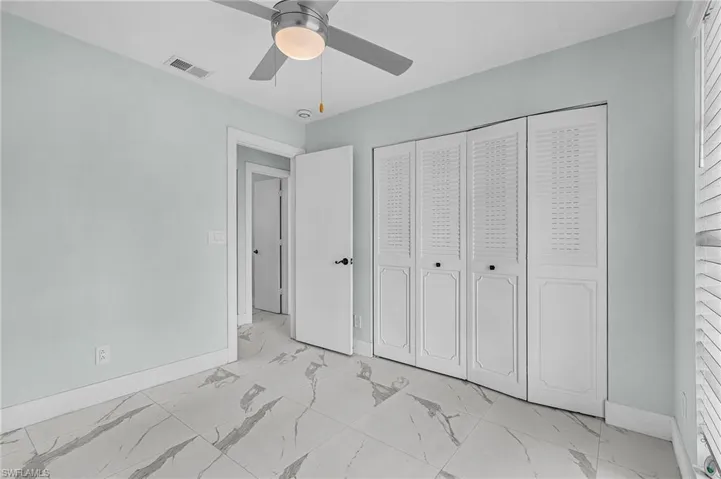 Unfurnished bedroom featuring marble finish floor, visible vents, a ceiling fan, a closet, and baseboards