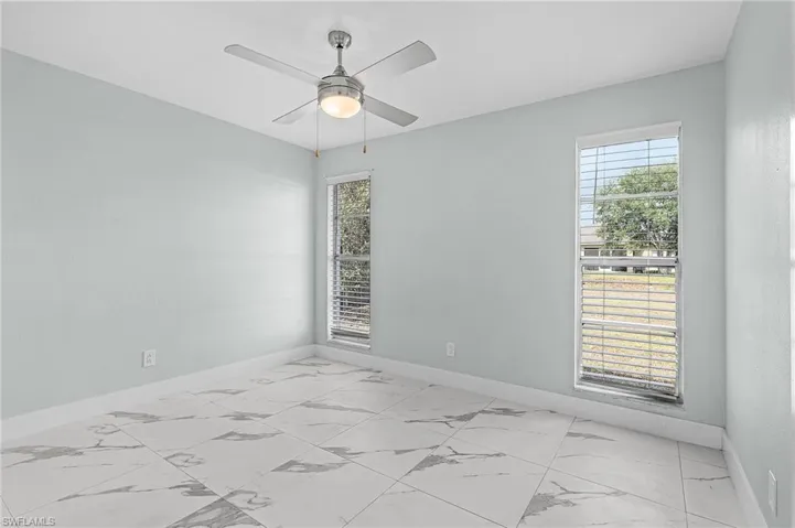 Empty room with marble finish floor, baseboards, and a healthy amount of sunlight