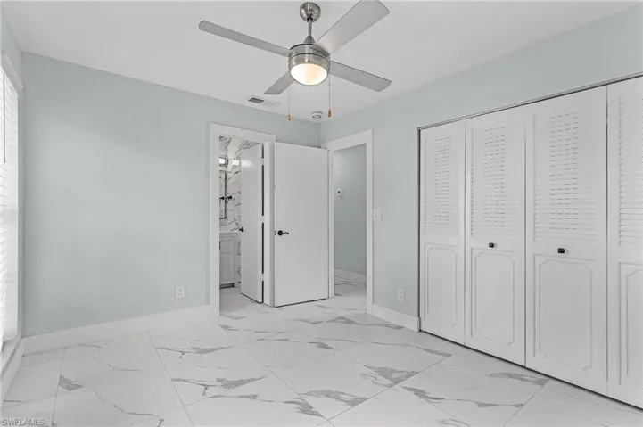 Unfurnished bedroom with marble finish floor, baseboards, visible vents, and a closet