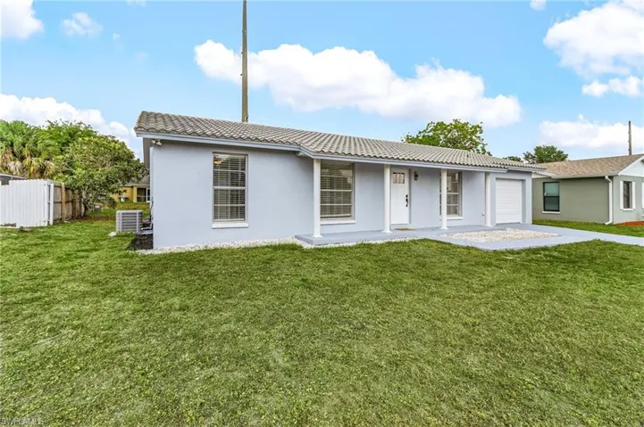 Back of house with stucco siding, a tile roof, fence, and a garage