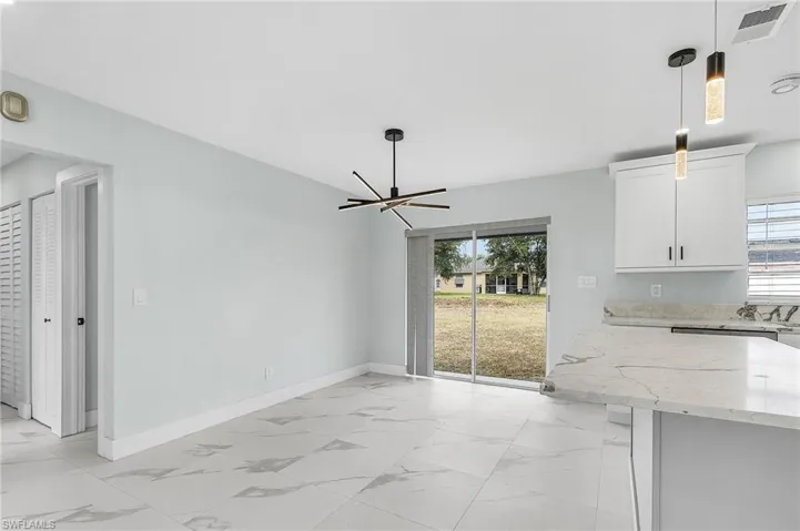 Unfurnished dining area featuring marble finish floor, baseboards, visible vents, and plenty of natural light