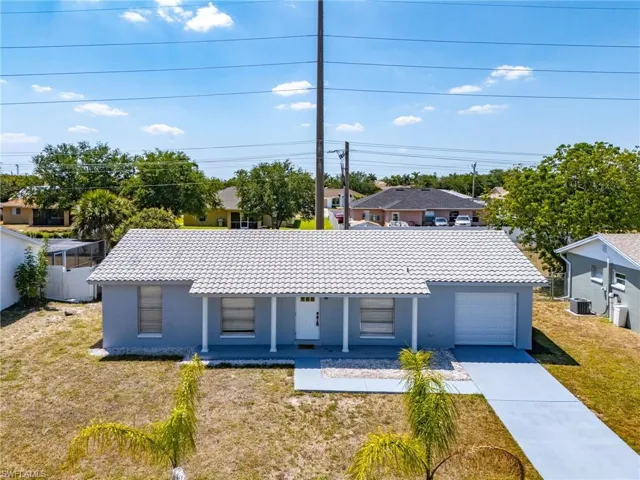Ranch-style home featuring a front lawn, stucco siding, concrete driveway, covered porch, and a garage