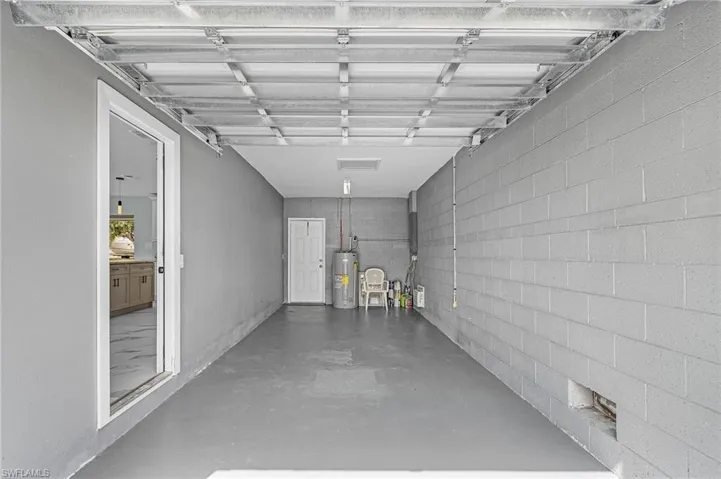 Garage featuring water heater and concrete block wall