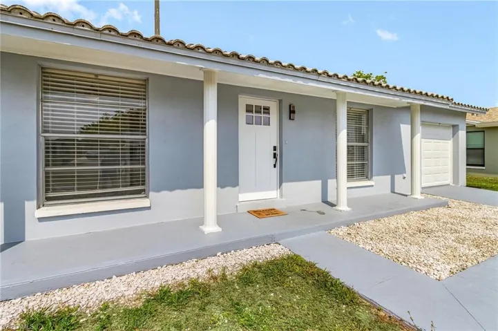 Entrance to property with a porch, a garage, and stucco siding