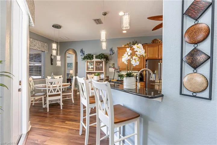 Kitchen with arched walkways, high quality fridge, visible vents, brown cabinetry, and decorative light fixtures