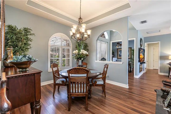 Dining space with dark wood-style floors, a raised ceiling, visible vents, and baseboards