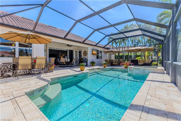 View of swimming pool with a patio, a pool with connected hot tub, ceiling fan, exterior bar, and a lanai