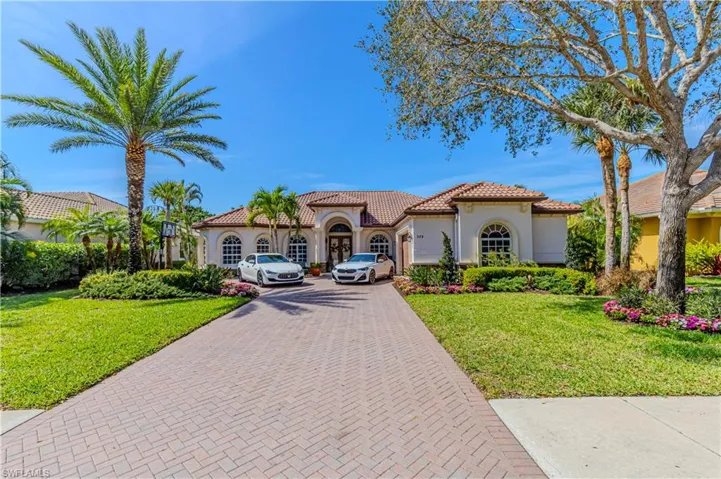 Mediterranean / spanish home featuring a front yard, decorative driveway, a tiled roof, and stucco siding