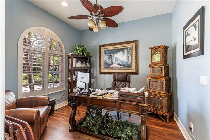 Office area with dark wood-style floors, a ceiling fan, and baseboards