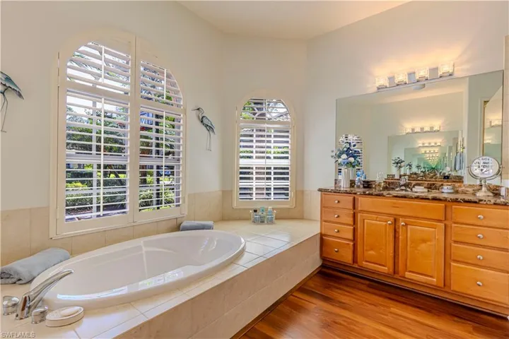 Bathroom with a garden tub, vanity, and wood finished floors
