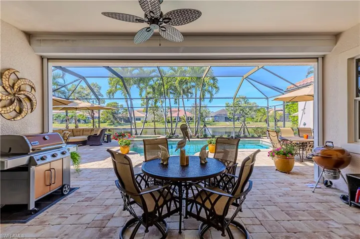 View of patio / terrace with outdoor dining area, a lanai, an outdoor hangout area, a pool with connected hot tub, and a ceiling fan