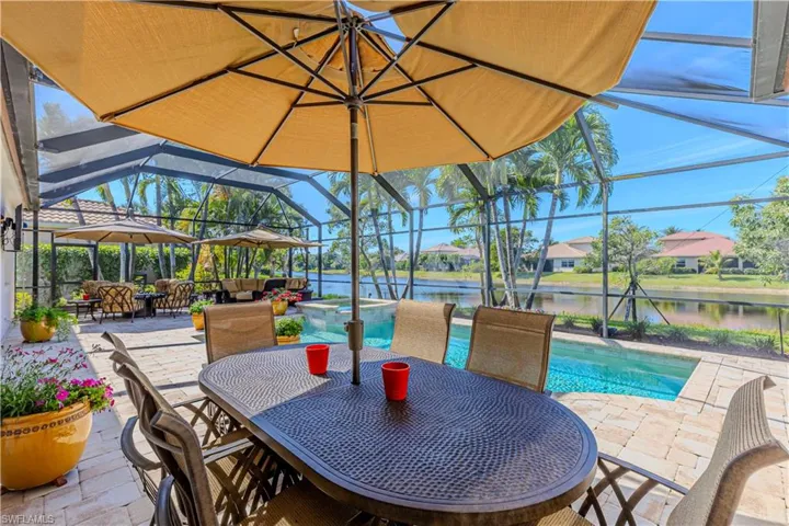 View of patio with a water view, a lanai, and a pool with connected hot tub