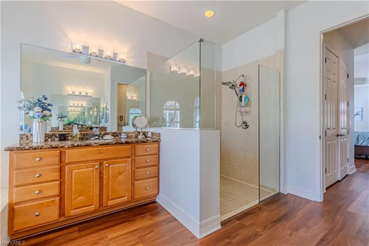 Full bath featuring baseboards, connected bathroom, wood finished floors, vanity, and a walk in shower