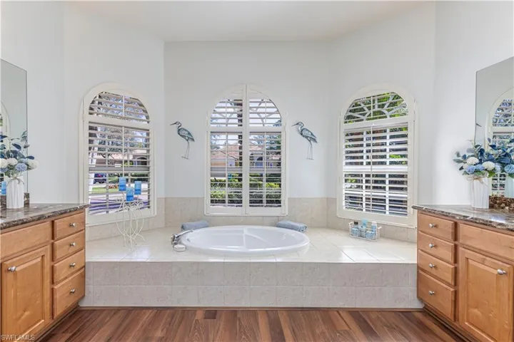 Bathroom featuring a garden tub, wood finished floors, and vanity