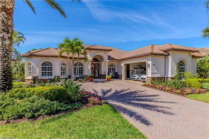 Mediterranean / spanish house featuring a garage, stone siding, a tiled roof, decorative driveway, and stucco siding