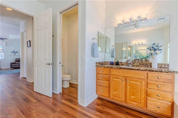 Bathroom with visible vents, toilet, ceiling fan, wood finished floors, and vanity