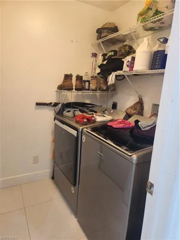 Washroom featuring washer and dryer and light tile flooring
