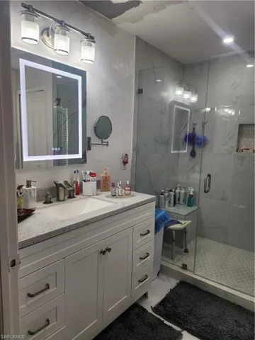 Bathroom with an enclosed shower, vanity, and tile floors