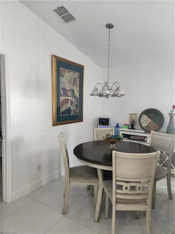 Dining area with tile floors, a chandelier, and vaulted ceiling