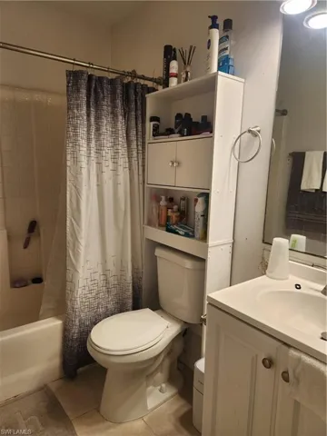 Full bathroom featuring tile floors, shower / bath combination with curtain, vanity, and toilet