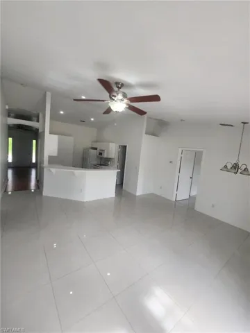 Unfurnished living room featuring light tile patterned floors and ceiling fan