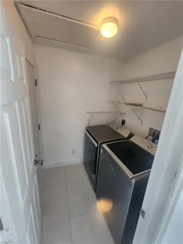 Laundry area with washer and clothes dryer and light tile patterned floors