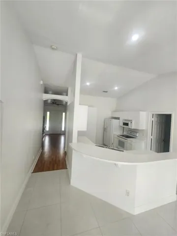 Kitchen with light hardwood / wood-style flooring, white appliances, lofted ceiling, white cabinetry, and ceiling fan