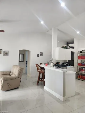 Kitchen with kitchen peninsula, white cabinets, and light tile floors