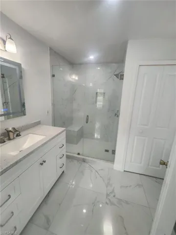 Bathroom featuring a shower with door, vanity, and tile patterned floors