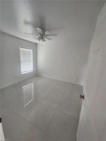 Tiled spare room featuring ceiling fan
