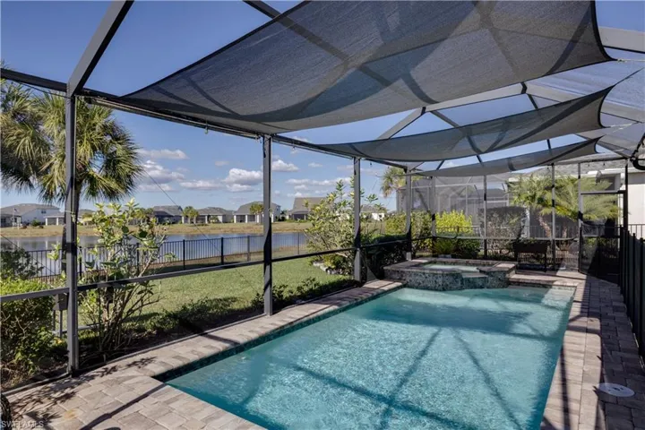 Screened lanai featuring a swimming pool and attached spa, surrounded by paver decking and pond view