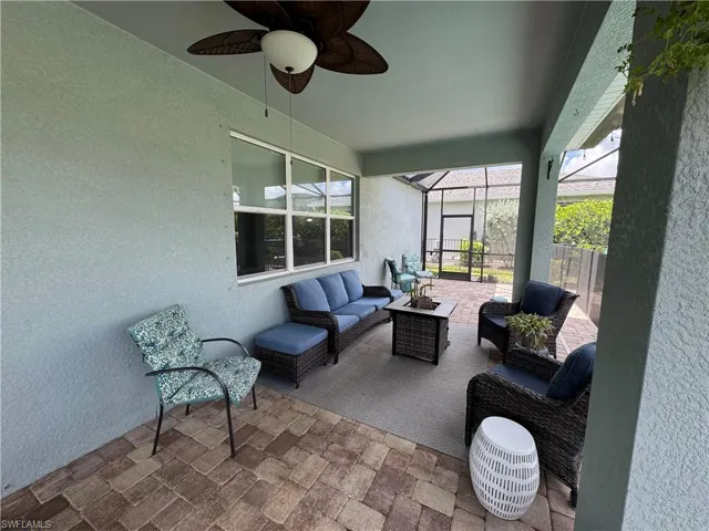 Spacious screened lanai featuring brick paver flooring, a ceiling fan with integrated lighting, and direct access to an outdoor area