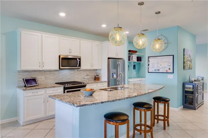 Kitchen featuring white cabinetry, stainless steel appliances, granite countertops, and a tiled backsplash