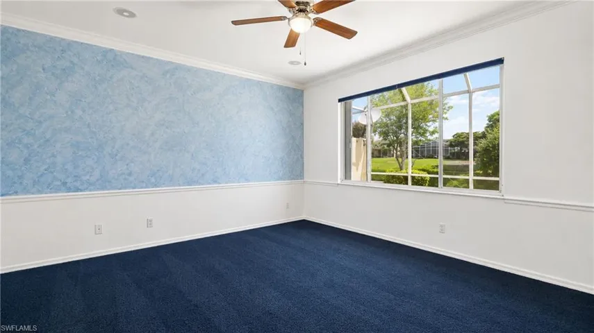 Room featuring a broad window with a green outdoor scenery, ceiling fan, crown molding, and two-tone wall treatment with a blue accent