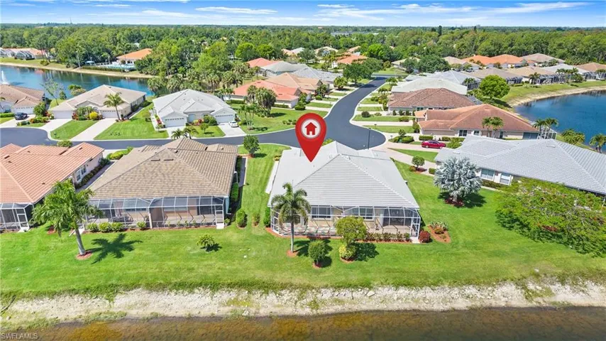Waterfront property featuring an expansive screened lanai, lush green lawn, mature palm trees, and a concrete driveway